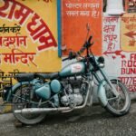 aged motorbike parked near weathered wall with paintings in city